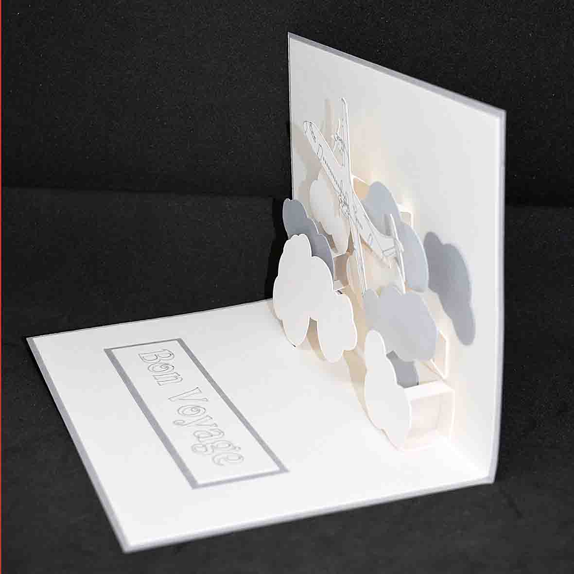 Carte blanche et grise en pop up pour un départ "bon voyage" motif avion et nuage